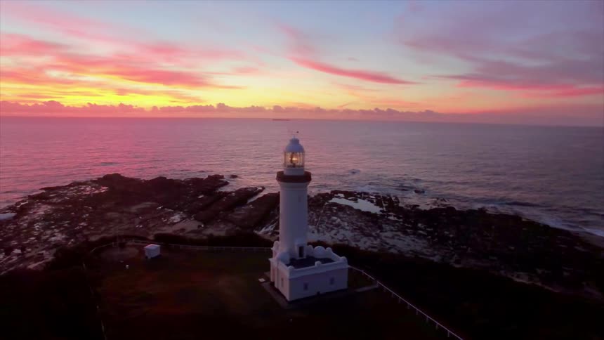 A Lighthouse guards the coast on a colorful dawn