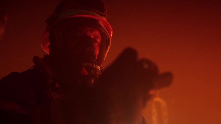 A firefighter in a burning building carefully moves something with his hand