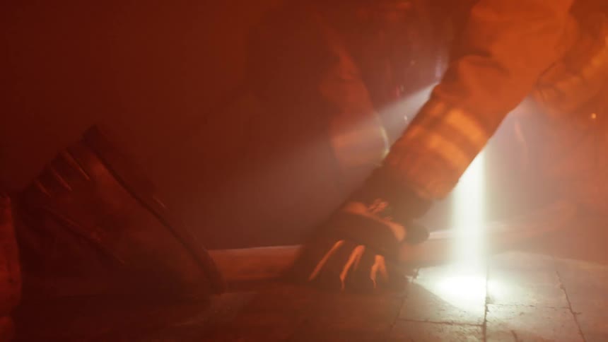 The firefighters crawl through the smoke filled room