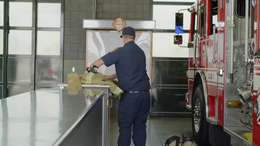 A firefighter putting down a coat then opening up a fire truck