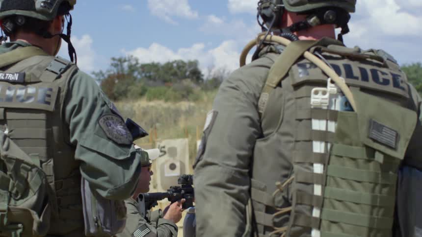 A military police knees to the ground and aims his gun
