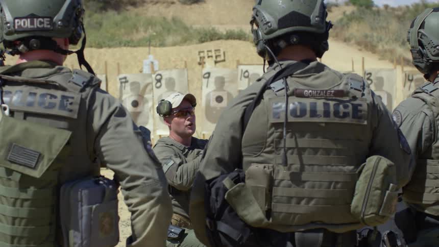 An outdoor firing range where policemen are receiving training with military gear