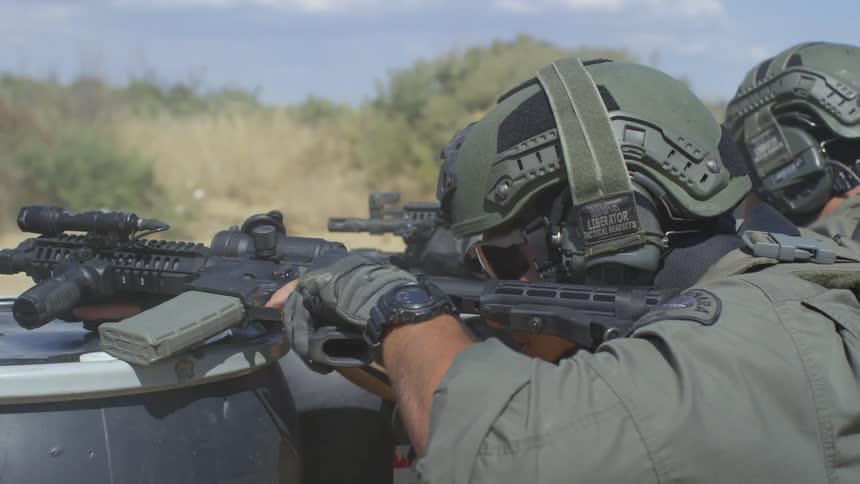 A pair of soldiers crouching behind barrels firing their assault rifles