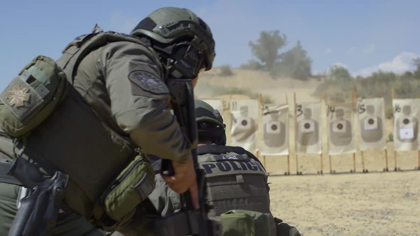 Two military police shoot at targets at a shooting range