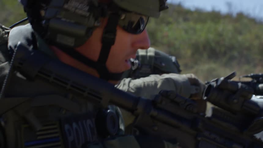 A soldier points his rifle over the barrel