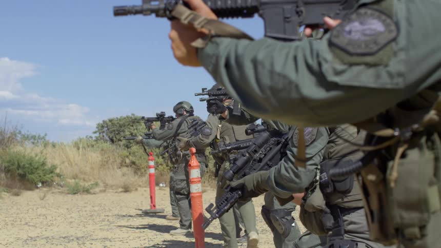 Group of police officers in military gear shoot assault rifles on a training exercise