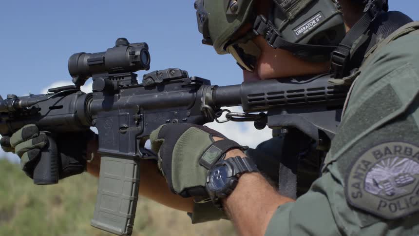 A police officer fires several rounds from an assault rifle