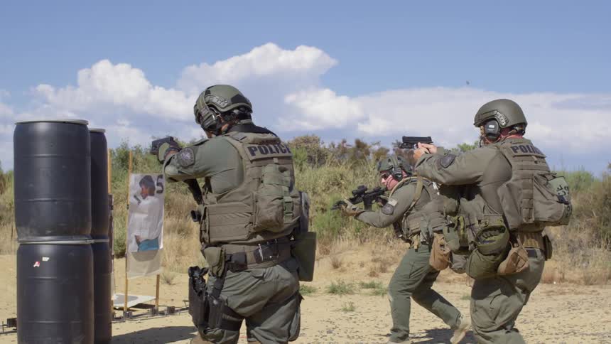 Police officers in military gear shoot firearms at targets in training exercise