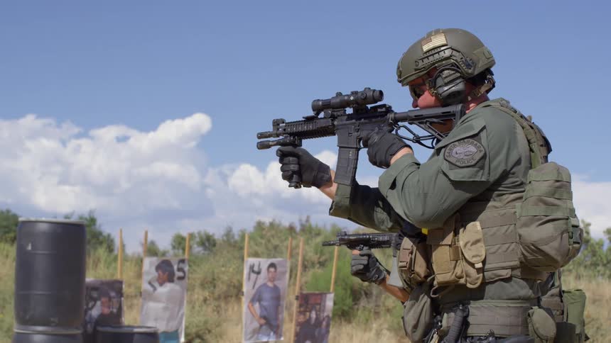 Two men in military uniforms shoot rifles