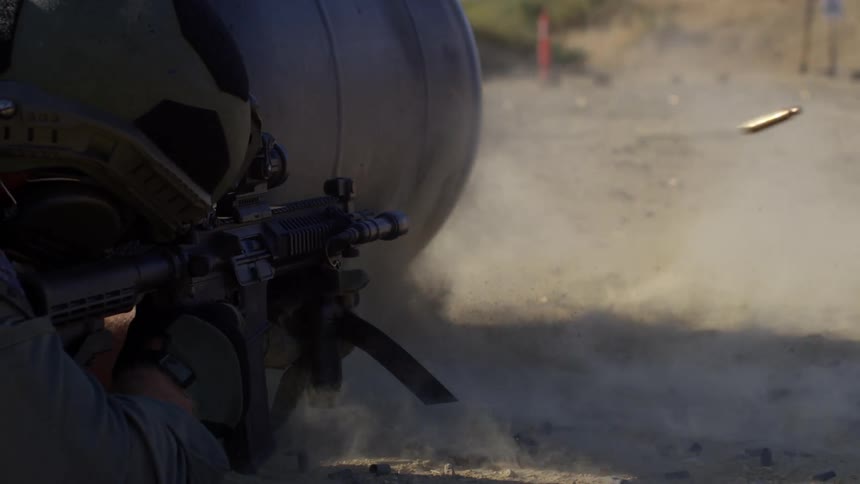 A soldier on the ground is firing his rifle