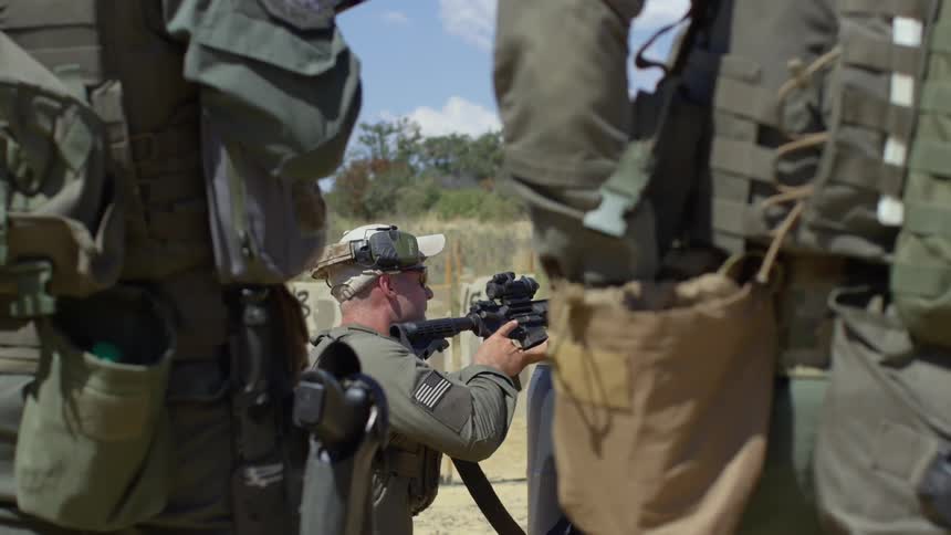 A soldier fires his gun as two others watch