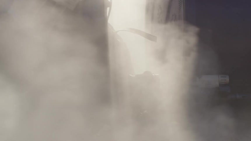 Police officer in military gear lays on the ground with an assault rifle surrounded by smoke