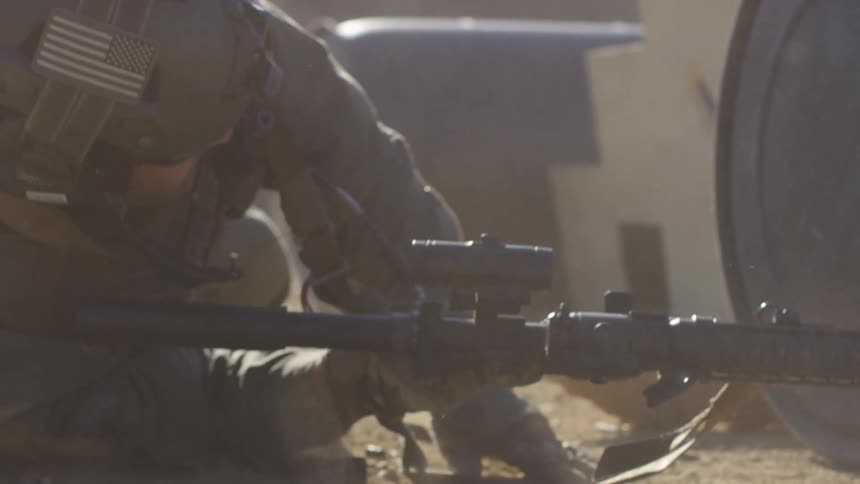 A military policeman drops to the ground as he takes cover and then raises his gun
