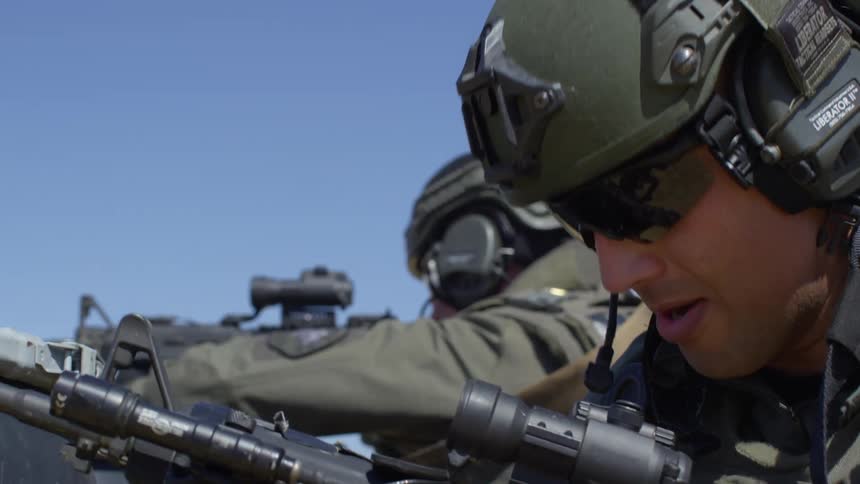 A police officer with a rifle looks closely at his gun