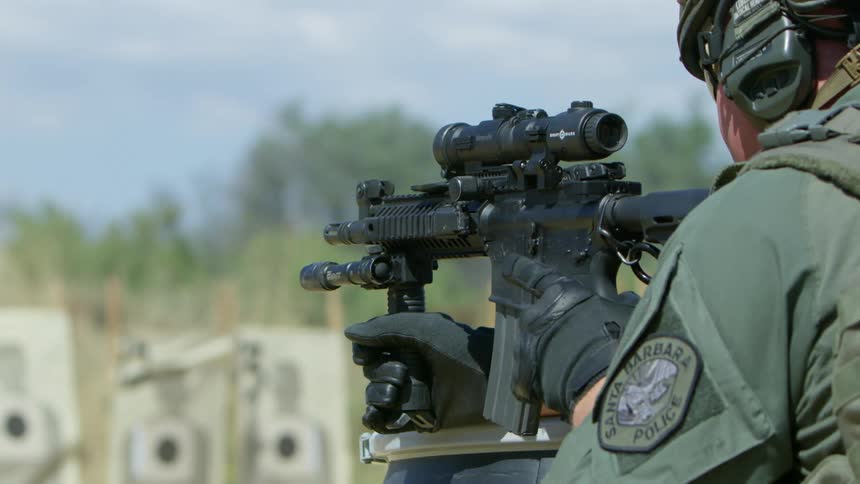 A police officer practices shooting with a machine gun at an outdoor range