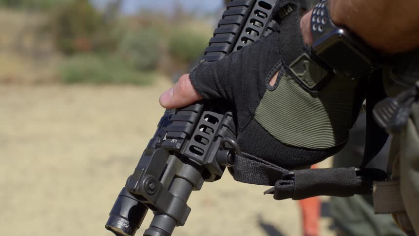 Police officers in military uniform hold assault weapons on a training exercise