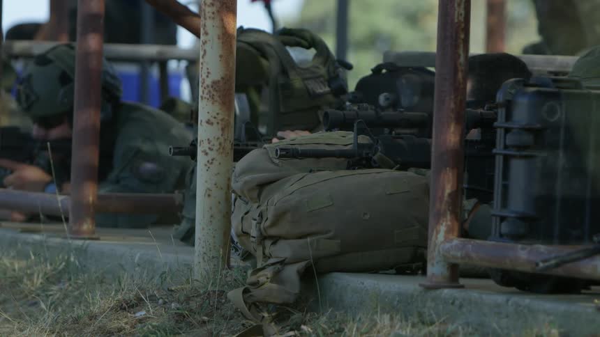People take cover as they fire rifles propped on sacks