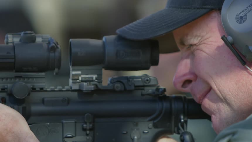 A man uses the scope on the rifle to fire