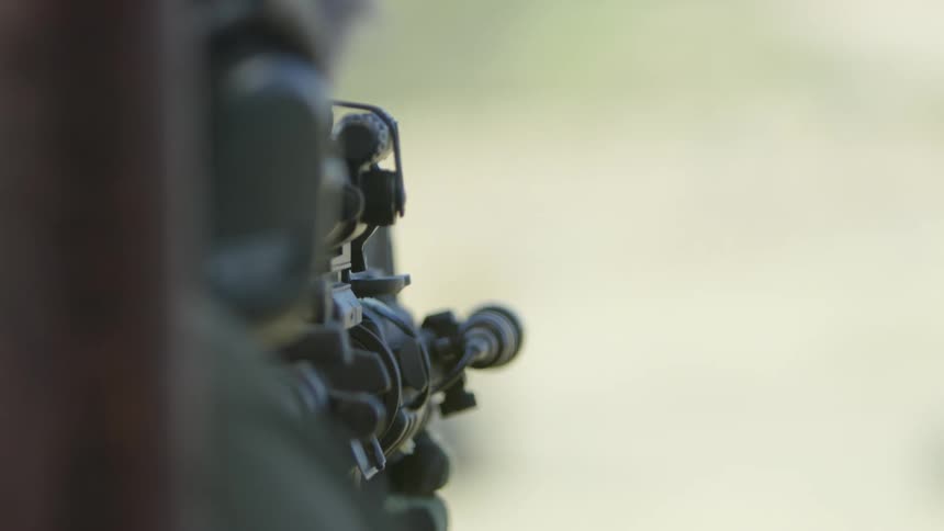 A person with gloves shooting a rifle with a scope