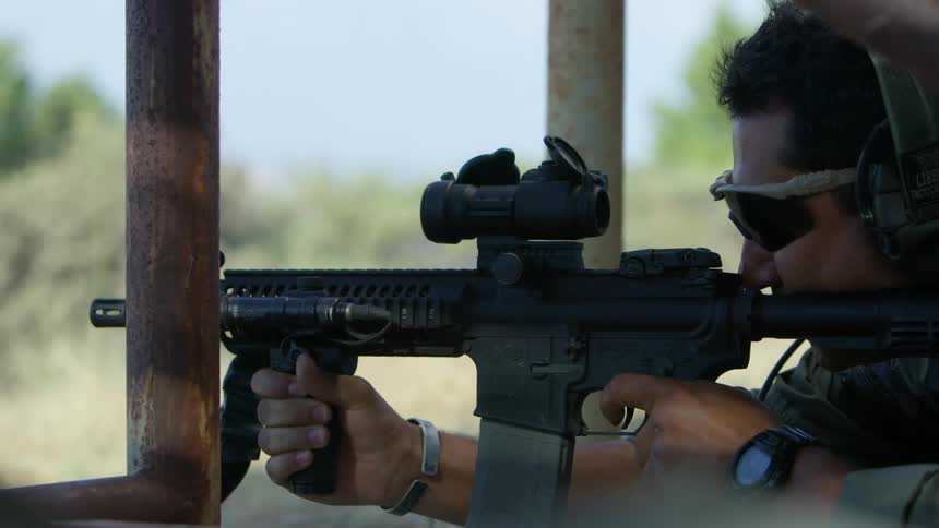 A soldier shoots his gun out of a building