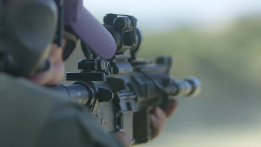 A police officer fires rounds from an assault rifle outdoors