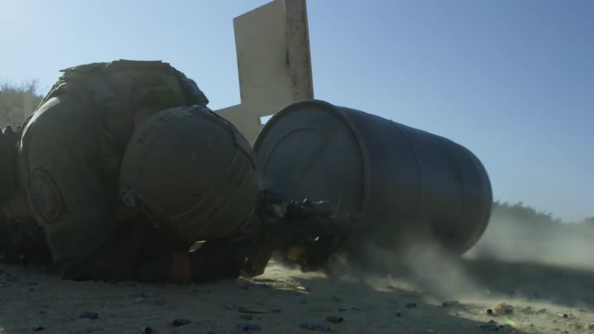 A military police lies on the ground and shoots his gun