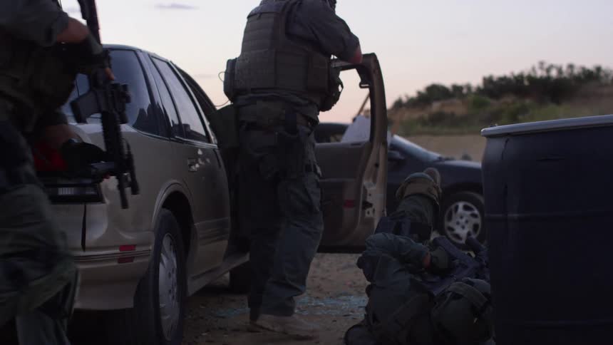 A swat team takes shelter behind a car door