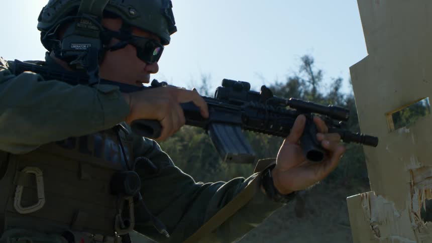 A military policeman removes his gun from behind a barrier