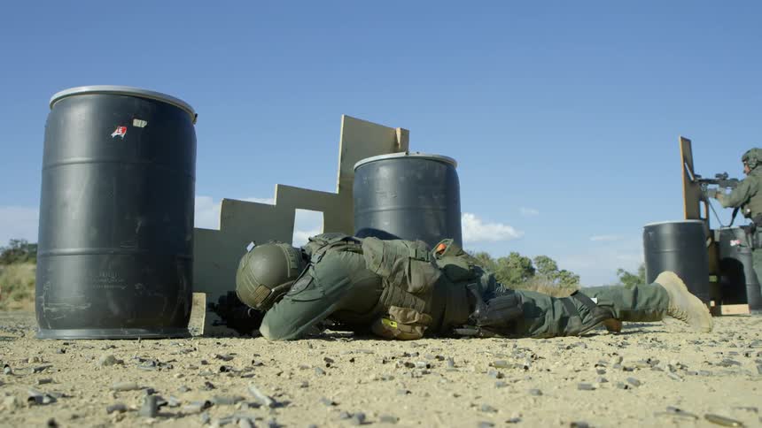 A soldier lays down and fires his rifle