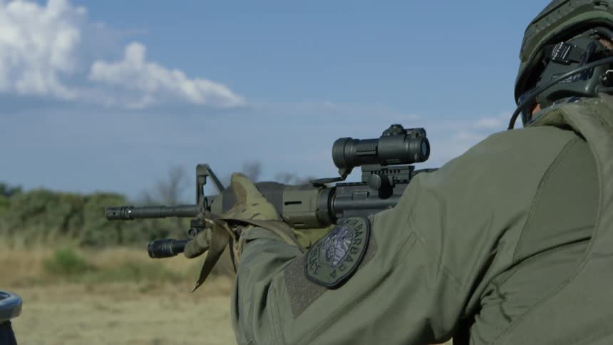 Police officer in military gear shoots an assault rifle in a training exercise