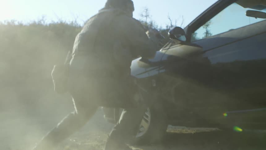 A policeman hides behind a car and then aims his gun