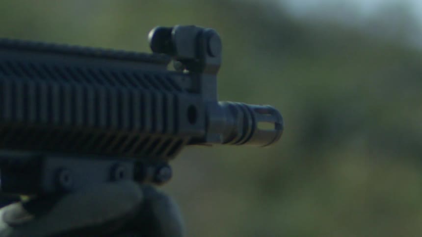 Smoke exits a military rifle as it is being shot