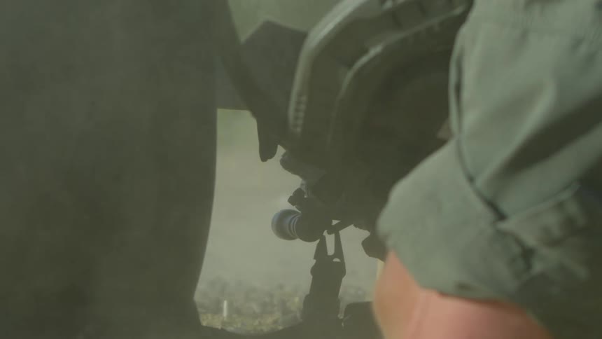 A person with a helmet and uniform shooting a rifle