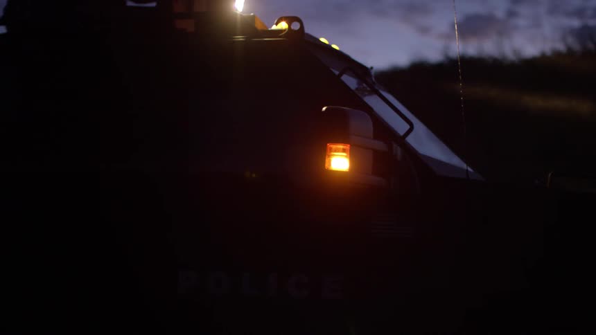 A swat team fires at a vehicle and advances toward a target on foot