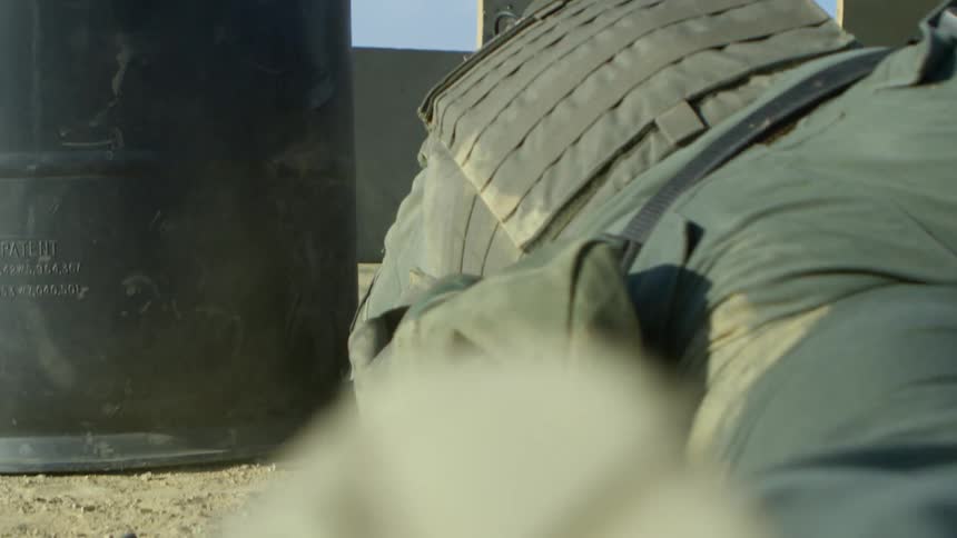 A soldier moves around behind a metal barrier on a shooting course