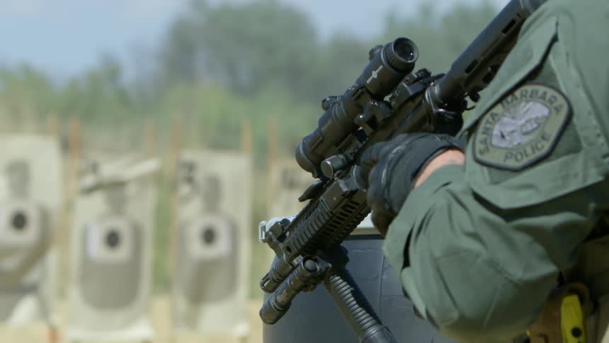 A police officer adjusting their firearm on an outdoor shooting range
