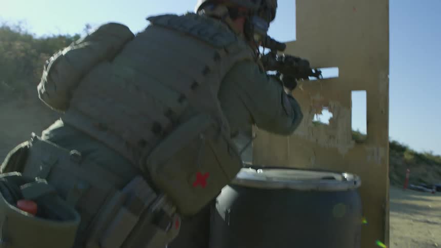 A soldier runs and ducks behind a board and aims his gun