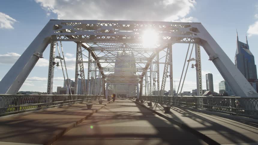 A person riding a bicycle approaches on a bridge with buildings and skyscrapers in the background