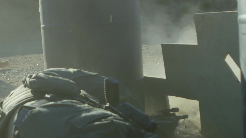 A soldier lies on the ground and fires his gun