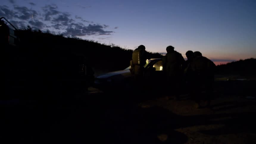 A swat team approaches a vehicle then walks backward as they retreat