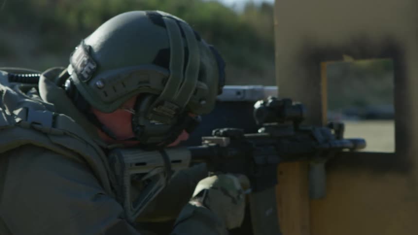 A military police runs and aims his gun and fires