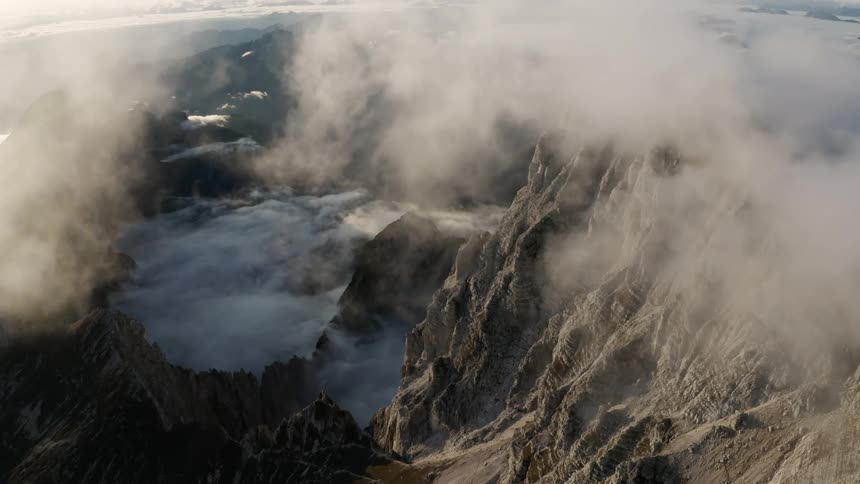 Aerial view of mountain range through the clouds at sunset