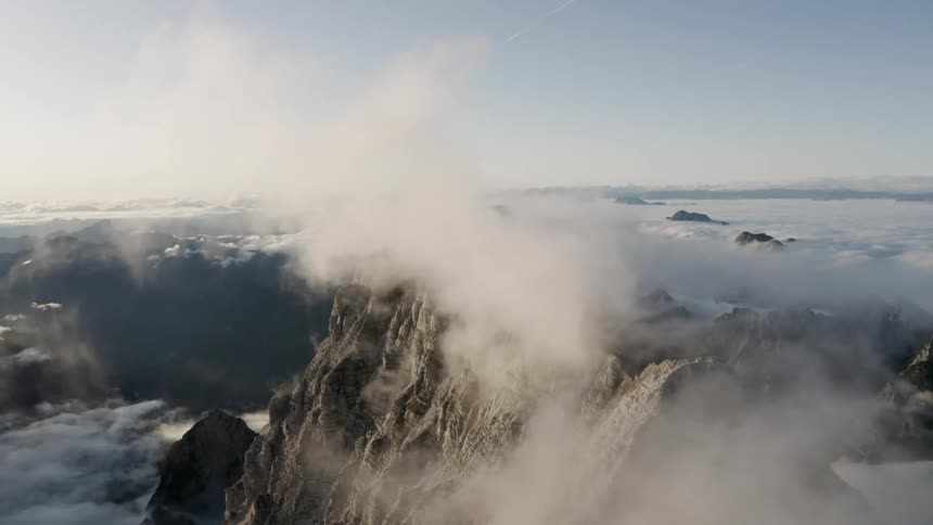 A mist forms over the peaks of snow covered mountains