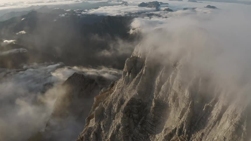 Aerial view of mountain range through the clouds at sunset
