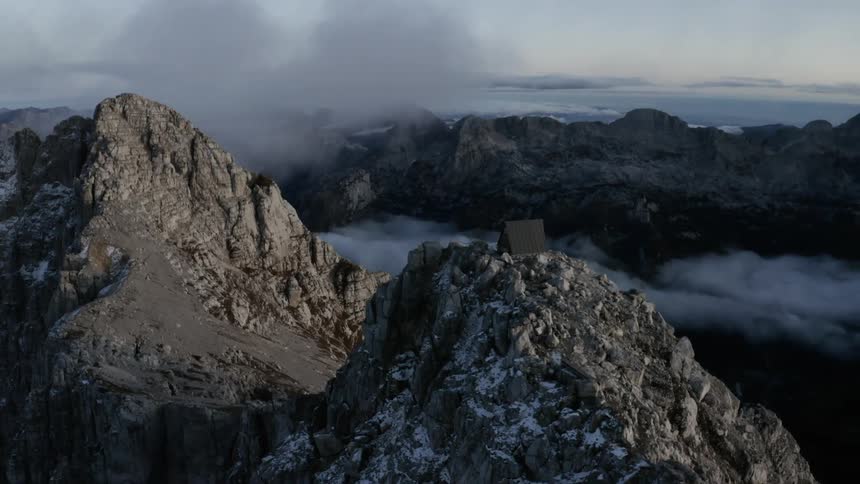 A gray mountain ridge with a small building on one peak
