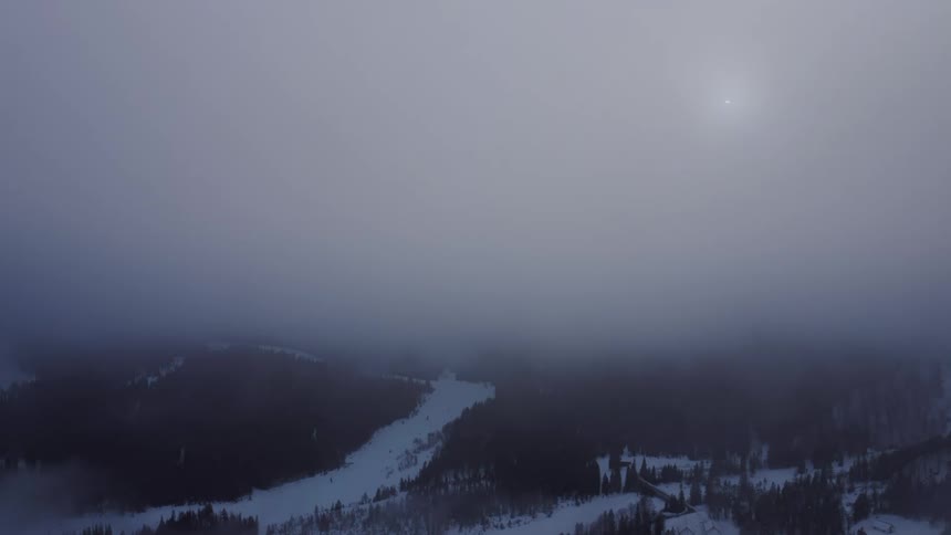 Clouds cover a snow covered forest
