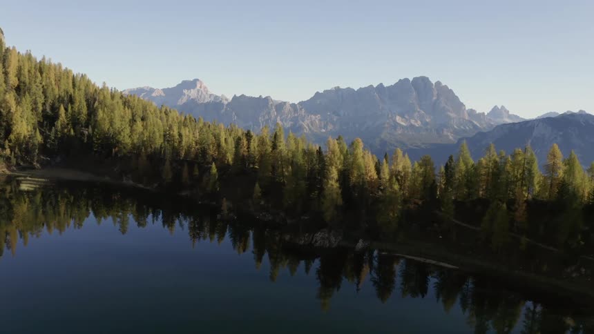 A pond with trees and mountains in the background