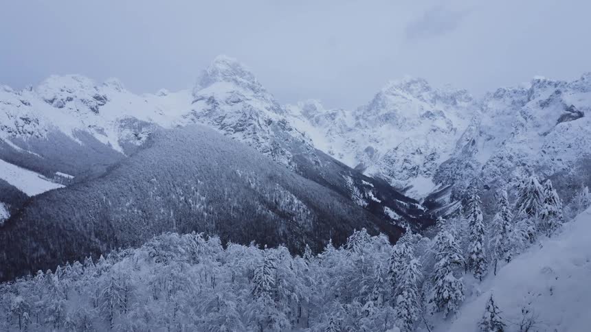 A winter storm covers a mountain and forest in snow and freezes a river