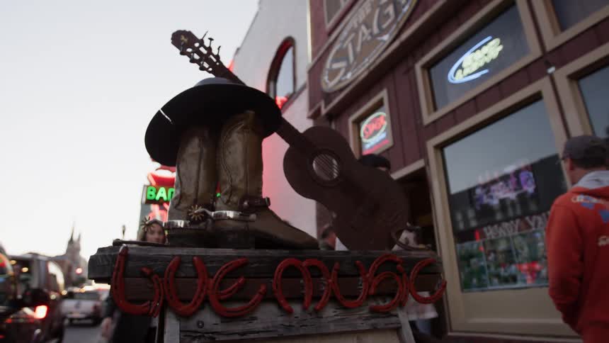 Pedestrians walk in front of town businesses and a musical statue