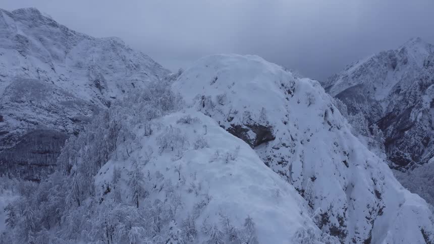 A snow covered mountain stands in front of a vast mountain range